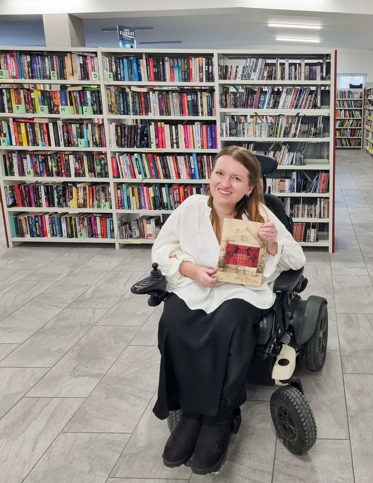 Sylwia Błach, autorka książki „Nie znajdziesz mnie po śladach stóp”, prezentuje książkę w bibliotece.